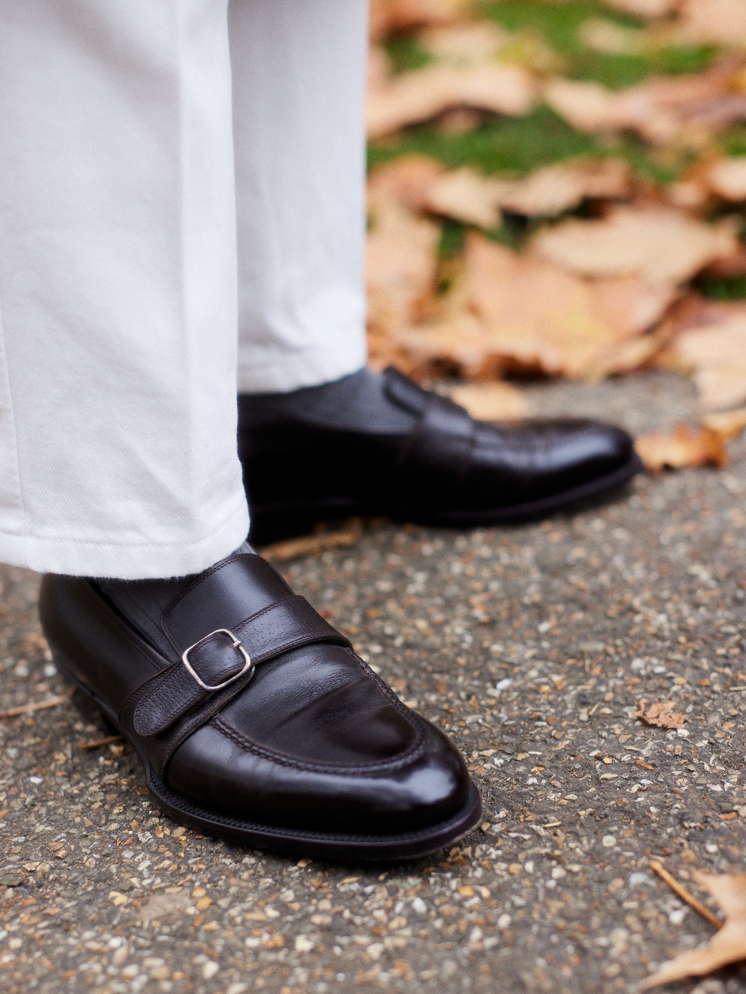 Buzz Tang, co-founder of The Anthology wearing shoes made in collaboration by Stefano Bemer, standing on the concrete road surrounded by fallen brown leaves, interview with A Collected Man London