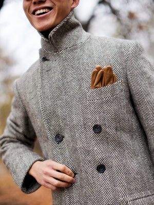 Buzz Tang wearing a grey coat with brown leather gloves in the breast pocket, that is a collaboration between his brand The Anthology and Permanent Style, interviewed by A Collected Man London