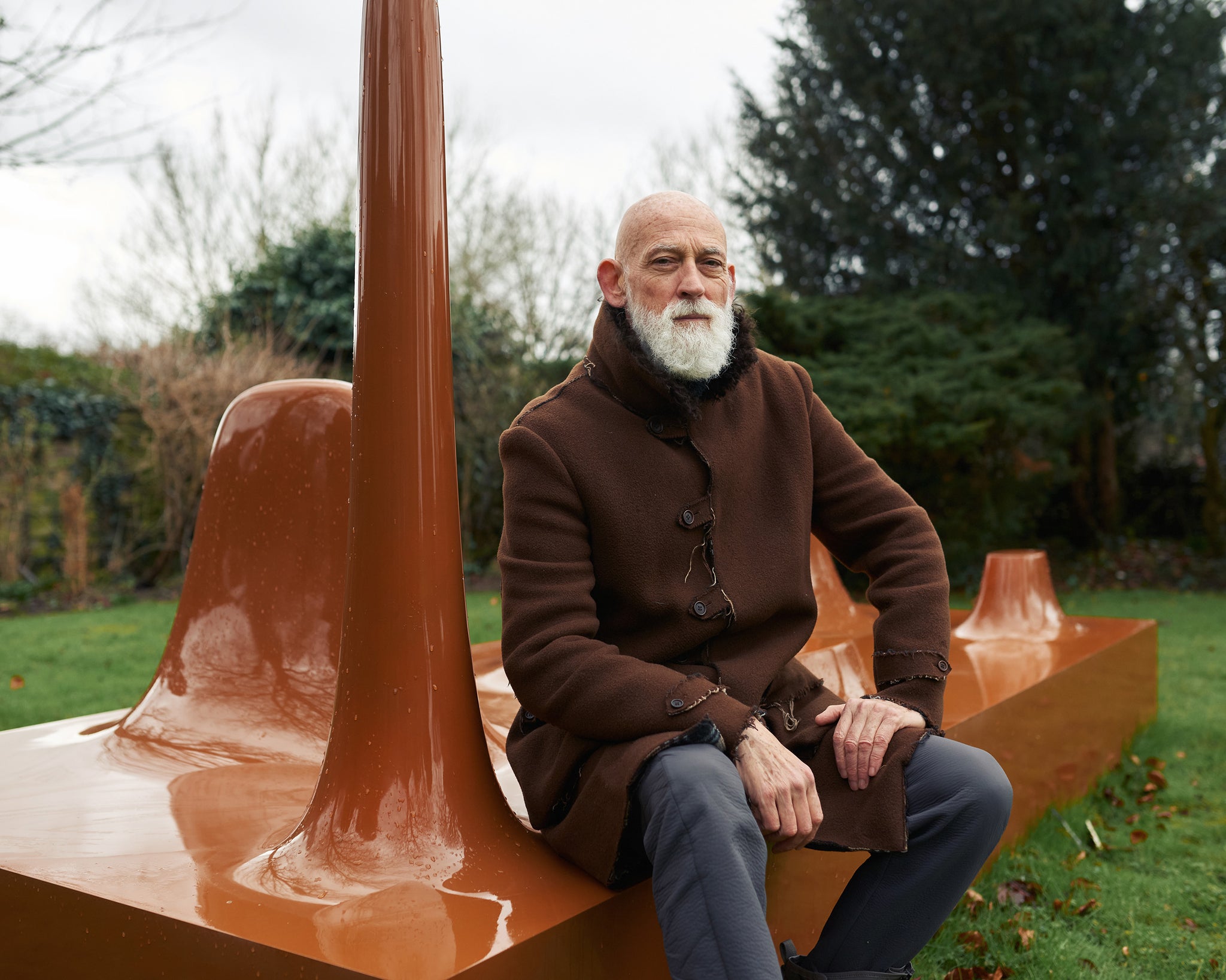 Ross Lovegrove, designer, sitting on a brown coloured structure in the outdoors interview with A Collected Man London